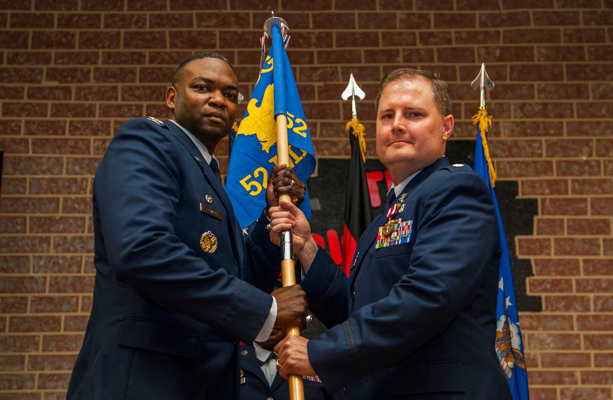 U.S. Air Force Col. Alfred Flowers, 52nd Medical Group commander, left, takes the ceremonial guidon from U.S. Air Force Lt. Col. Wade Adair, outgoing 52nd Medical Support Squadron commander, during the 52nd MDSS change of command ceremony in the Brickhouse on Spangdahlem Air Base, Germany, June 30, 2016. The guidon symbolized the authority Flowers placed on Adair, who then relinquished command over the 52nd MDSS as the flag exchanged hands. (U.S. Air Force photo by Airman 1st Class Timothy Kim/Released)