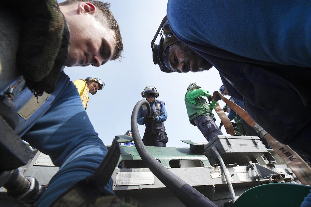 Sailors stow fire hoses during an aircraft fire drill on the flight deck of the amphibious assault ship USS Boxer in the Arabian Gulf, July 5, 2016. Navy photo by Petty Officer 2nd Class Debra Daco