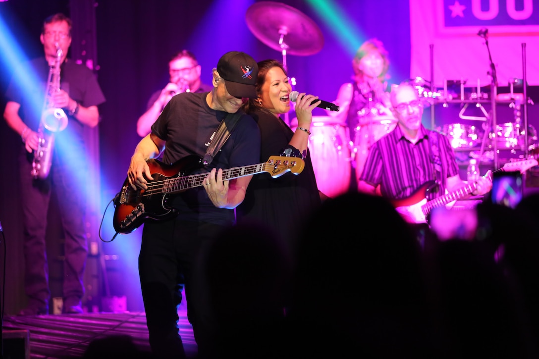 Gary Sinise and Mari Anne Jayme stand back-to-back as they perform on the Two Rivers Theater stage at Marine Corps Air Station Cherry Point, N.C., July 5, 2016. Gary Sinise and the Lt. Dan Band have participated in 70 United Service Organization tours since they came together. In total, they have entertained more than 363,000 service members and military families in 13 countries. The band puts on shows to raise spirits, funds and awareness for severely wounded warriors in need. Sinise plays the elecric bass and Jayme is a vocalist with the Lt. Dan Band. (U.S. Marine Corps photo by Lance Cpl. Mackenzie Gibson/Released)