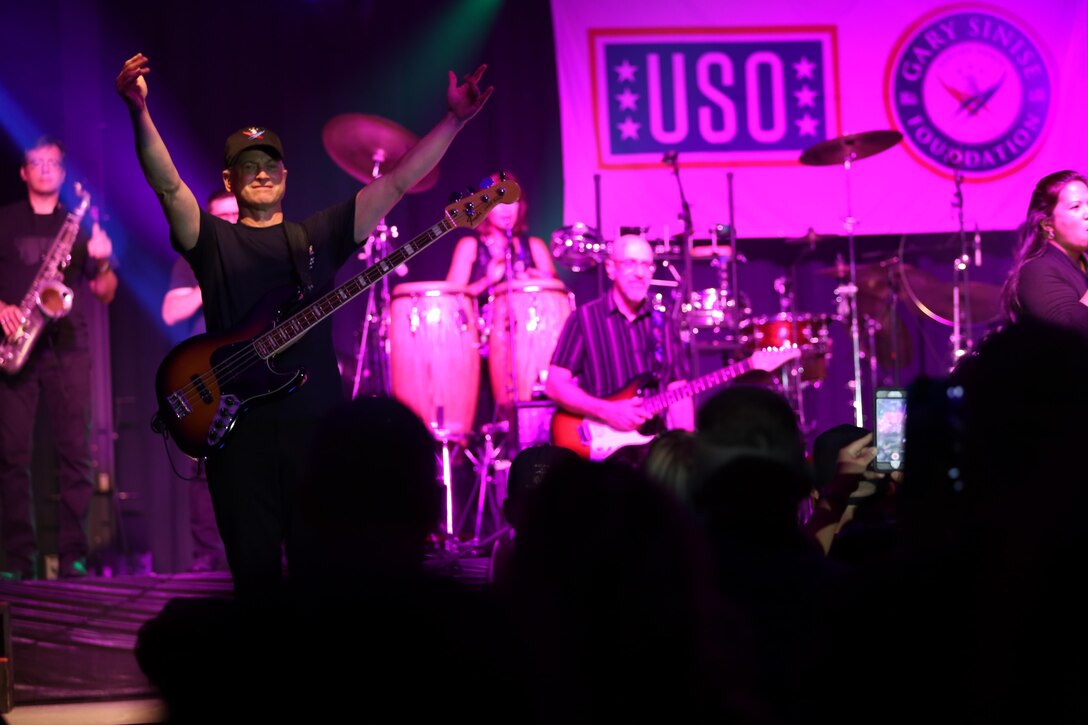 Gary Sinise waves for the crowd to come closer during a performance on the Two Rivers Theater stage at Marine Corps Air Station Cherry Point, N.C., July 5, 2016. Gary Sinise and the Lt. Dan Band have participated in 70 United Service Organization tours since they came together. In total, they have entertained more than 363,000 service members and military families in 13 countries. The band puts on shows to raise spirits, funds and awareness for severely wounded warriors in need. Gary Sinise plays the elecric bass with Gary Sinise and the Lt. Dan Band. (U.S. Marine Corps photo by Lance Cpl. Mackenzie Gibson/Released)