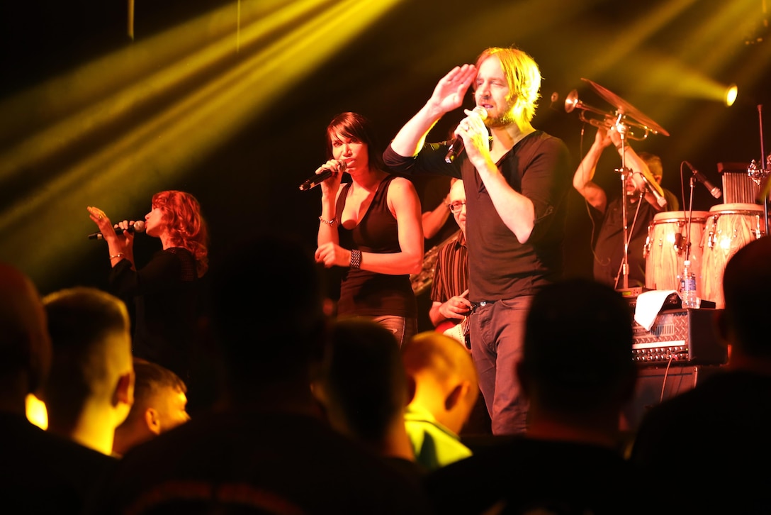 Lt. Dan Band members Dan Myers (right), Molly Callinan (center) and Julie Dutchak (left) sing during a performance on the Two Rivers Theater stage at Marine Corps Air Station Cherry Point, N.C., July 5, 2016. Gary Sinise and the Lt. Dan Band have participated in 70 United Service Organization tours since they came together. In total, they have entertained more than 363,000 service members and military families in 13. The band puts on shows to raise spirits, funds and awareness for severely wounded warriors in need. Myers, Callinan and Dutchak are musicians with Gary Sinise and the Lt. Dan Band. (U.S. Marine Corps photo by Lance Cpl. Mackenzie Gibson/Released)