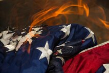 An American flag sets fire during a flag-burning ceremony at Minot Air Force Base, N.D., June 29, 2016. Flag-burning ceremonies are held to properly dispose of worn or tattered flags. Minot Airmen partnered with Girl Scouts to perform the ceremony, which was held in honor of Flag Day. (U.S. Air Force photo/Senior Airman Apryl Hall)