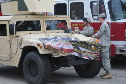 Master Sgt. Keith Clark, left, and Sgt. Adam Burson affixes the banner for the 416th Theater Engineer Command to their Humvee in preparation for the Independence Day parade in Villa Park, Illinois, Jul. 4, 2016. (U.S. Army photo by Spc. Brianna Saville/Released)