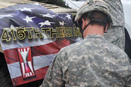 Master Sgt. Keith Clark affixes the banner for the 416th Theater Engineer Command to their Humvee in preparation for the Independence Day parade in Villa Park, Illinois, Jul. 4, 2016. (U.S. Army photo by Spc. Brianna Saville/Released)