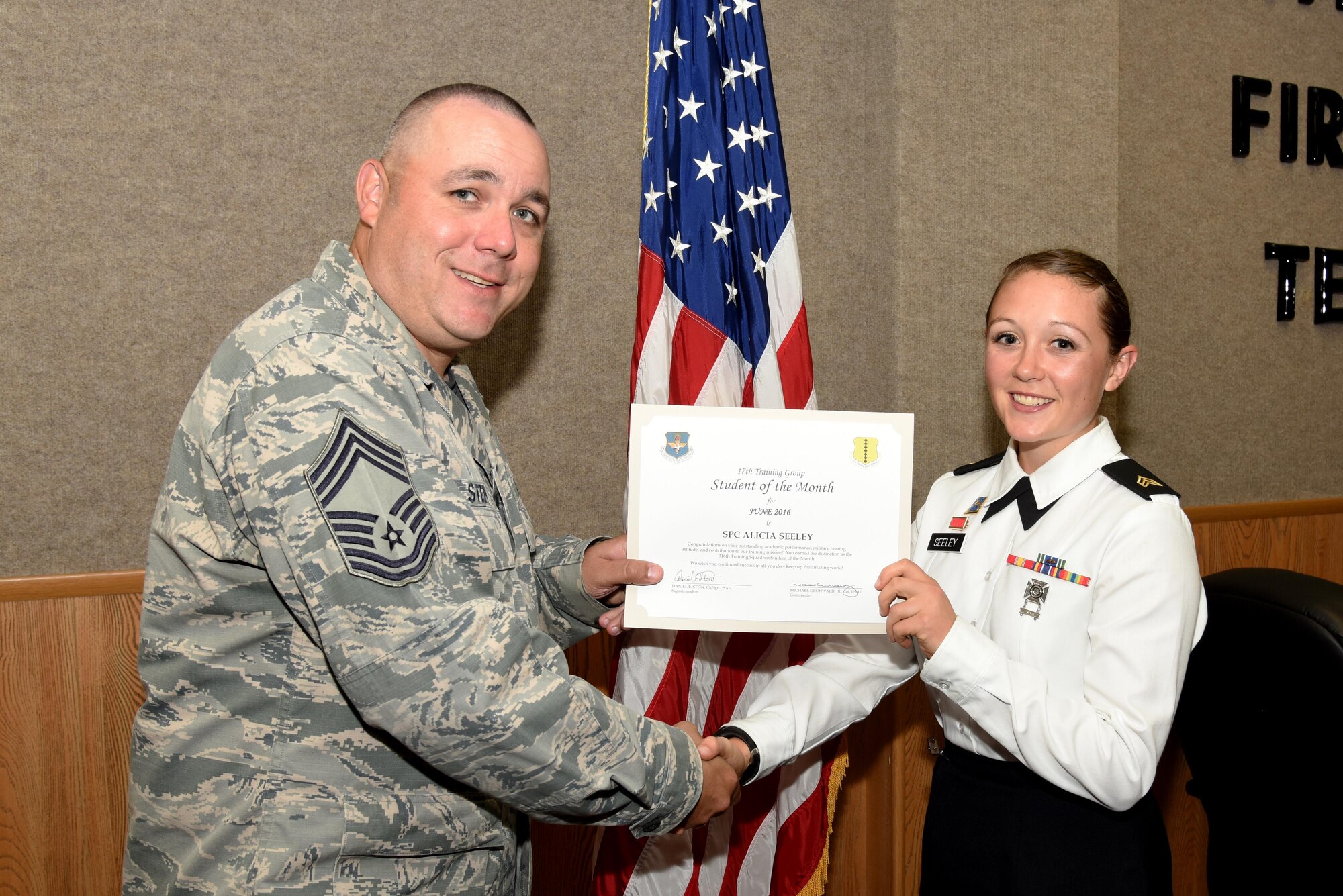 U.S. Air Force Chief Master Sgt. Daniel Stein, 17th Training Group superintendent, presents the 316th Training Squadron Student of the Month award for June 2016 to Army Sgt. Alicia Seeley in Brandenburg Hall on Goodfellow Air Force Base, Texas, July 1, 2016. (U.S. Air Force photo by Senior Airman Joshua Edwards/Released) 