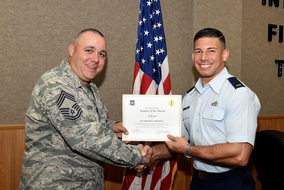 U.S. Air Force Chief Master Sgt. Daniel Stein, 17th Training Group superintendent, presents the 315th Training Squadron Officer Student of the Month award for June 2016 to 2nd Lt. Michael Dezinna in Brandenburg Hall on Goodfellow Air Force Base, Texas, July 1, 2016. (U.S. Air Force photo by Senior Airman Joshua Edwards/Released)