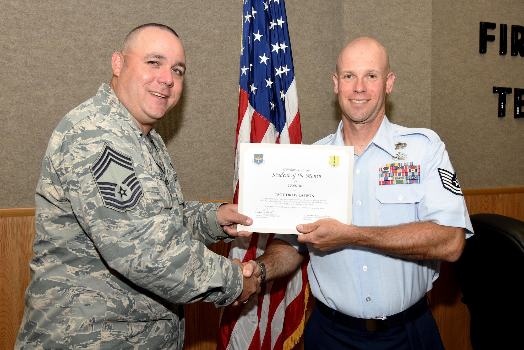 U.S. Air Force Chief Master Sgt. Daniel Stein, 17th Training Group superintendent, presents the 312th Training Squadron Student of the Month award for June 2016 to Tech. Sgt. Drew Layson in Brandenburg Hall on Goodfellow Air Force Base, Texas, July 1, 2016. (U.S. Air Force photo by Senior Airman Joshua Edwards/Released)