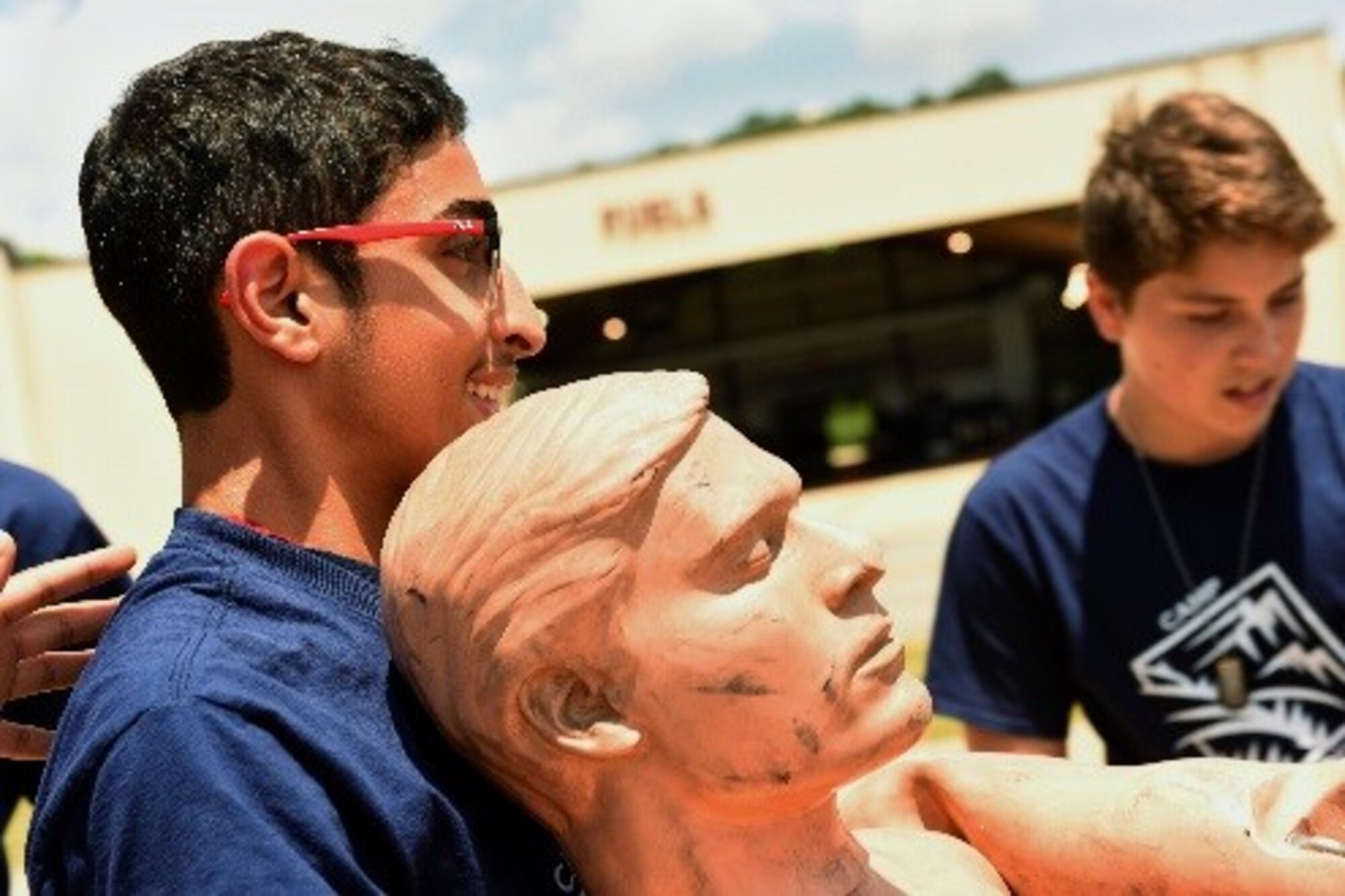 Camp Confidence students learn and practice the fireman carry with a dummy during a base tour, June 27, 2016, at Seymour Johnson Air Force Base, North Carolina. The Camp Confidence program aims to show youth careers that are available to good-standing citizens. (U.S. Air Force photo/Airman 1st Class Ashley Williamson)