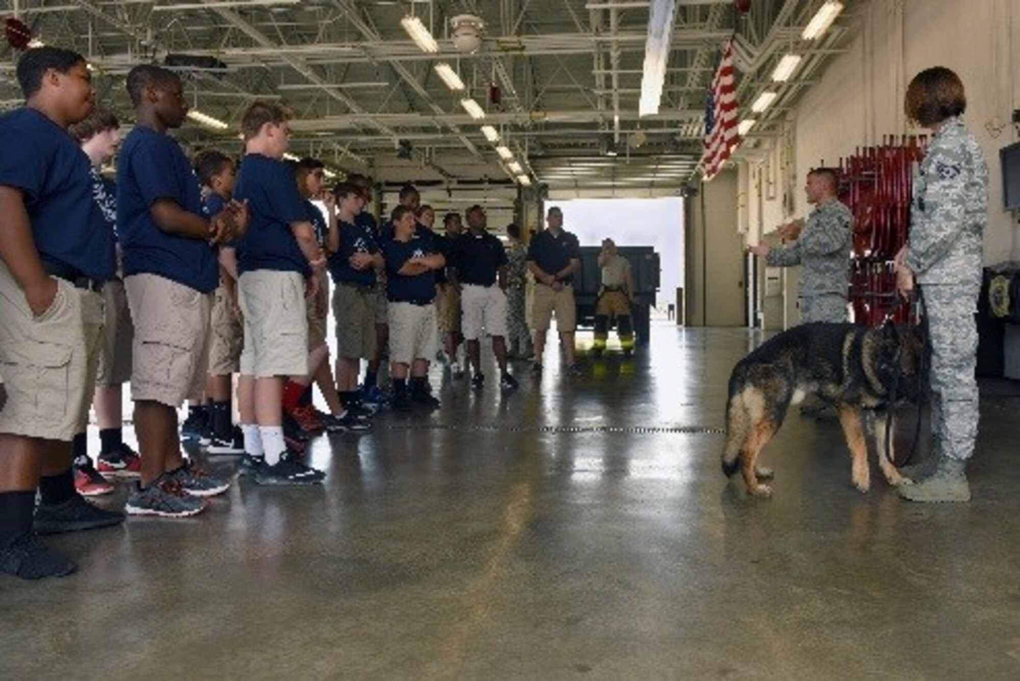 Staff Sgt. Nicole Gilley (far right), 4th Security Forces Squadron military working dog trainer, and Staff Sgt. John Makripodis, 4th SFS kennel master, demonstrate basic dog commands to Camp Confidence students during a base tour, June 27, 2016, at Seymour Johnson Air Force Base, North Carolina. The Camp Confidence program allows students to tour various careers around the state as well as military installations. (U.S. Air Force photo/Airman 1st Class Ashley Williamson)