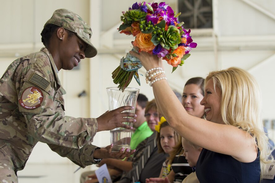 U.S. Air Force Master Sgt. Angelique Joiner, 81st Fighter Squadron NCO in charge of aviation resource management, presents flowers to Leigh Hogan, wife of Lt. Col. Jeffrey Hogan, 81st FS outgoing commander, during a change of command ceremony, July 7, 2016, at Moody Air Force Base, Ga. Hogan and his family will transition to Washington, D.C. where he will attend National War College. (U.S. Air Force photo by Senior Airman Ceaira Tinsley/ Released)