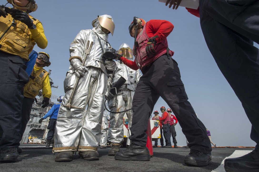 Navy Petty Officer 2nd Class Uriel Samanoescava, right, teachers sailors how to fight a fire during an aircraft fire drill on the flight deck of the amphibious assault ship USS Boxer in the Arabian Gulf, July 7, 2016. The Boxer is supporting Operation Inherent Resolve, maritime security operations and theater cooperation efforts in the U.S. 5th Fleet area of operations. Navy photo by Petty Officer 2nd Class Debra Daco