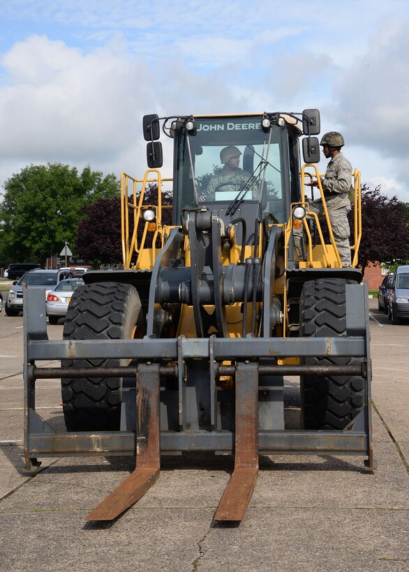 U.S. Air Force Senior Airman Dishawn Harvey, right, 100th Civil Engineer Squadron Pavements and Construction Equipment heavy equipment operator, instructs U.S. Air Force Airman 1st Class Luke Sarafian, 100th CES Readiness and Emergency Management apprentice, on how to operate a front-end loader with fork attachments June 30, 2016, during the 100th CES annual Prime Base Engineering Emergency Force training on RAF Mildenhall, England. Airmen from the 100th CES trained on a variety of equipment and situations, including driving a Humvee, operating heavy machinery, land navigation, and high- and low-crawling. (U.S. Air Force photo by Karen Abeyasekere/Released)