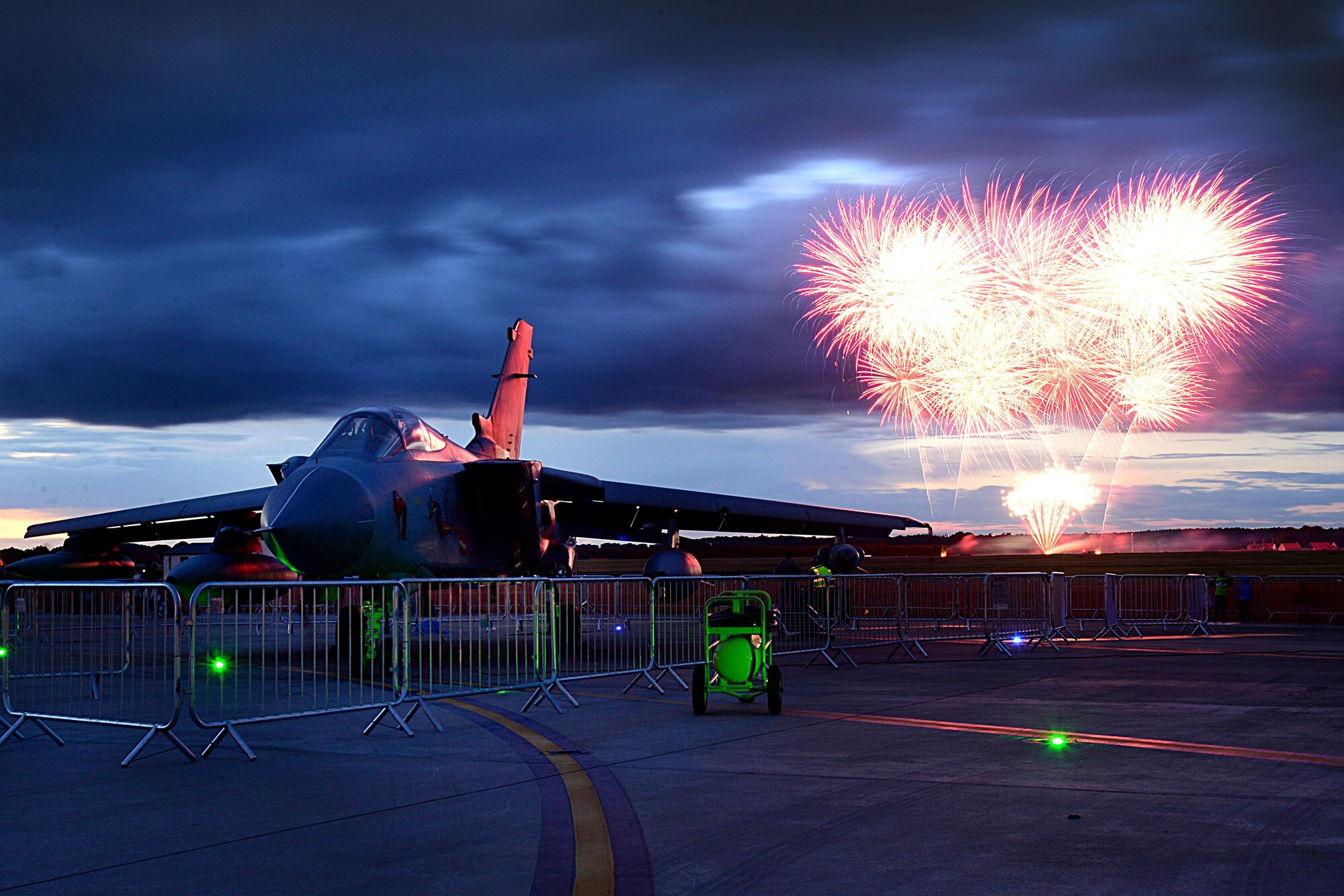 A fireworks display ignites beyond a Royal Air Force Tornado aircraft static display during the Wings and Wheels event at RAF Lakenheath, England, July 2. Airmen along with their families and guests were treated to a classic car show, carnival rides, static aircraft displays and a jump by the RAF Falcons parachute display team. (U.S. Air Force photo/Tech. Sgt. Matthew Plew)