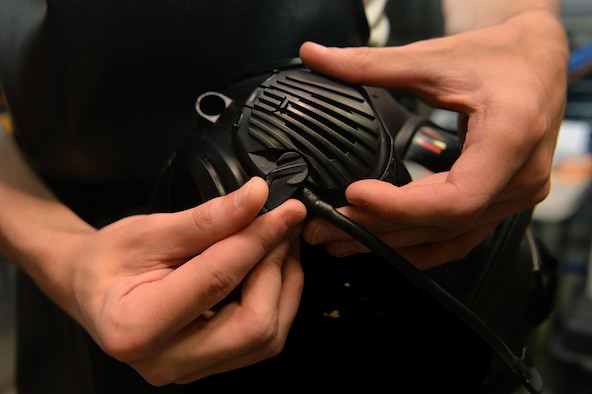 Airman 1st Class Maxwell Dean, a material management apprentice with the 1st Special Operations Logistics Readiness Squadron, removes the outlet valve cover of a gas mask before sanitization at Hurlburt Field, Fla., July 7, 2016. The valve must be removed for sanitization to ensure all internal components of the mask are properly cleaned. (U.S. Air Force photo by Senior Airman Andrea Posey)