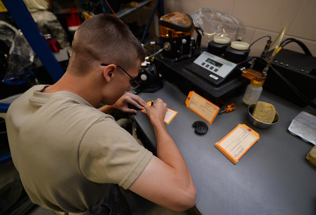 Airman 1st Class Maxwell Dean, a material management apprentice with the 1st Special Operations Logistics Readiness Squadron, writes on a serviceable tag at Hurlburt Field, Fla., July 7, 2016. A serviceable tag is a record attached to a gas mask that informs material managers the date a mask was last tested. (U.S. Air Force photo by Senior Airman Andrea Posey)