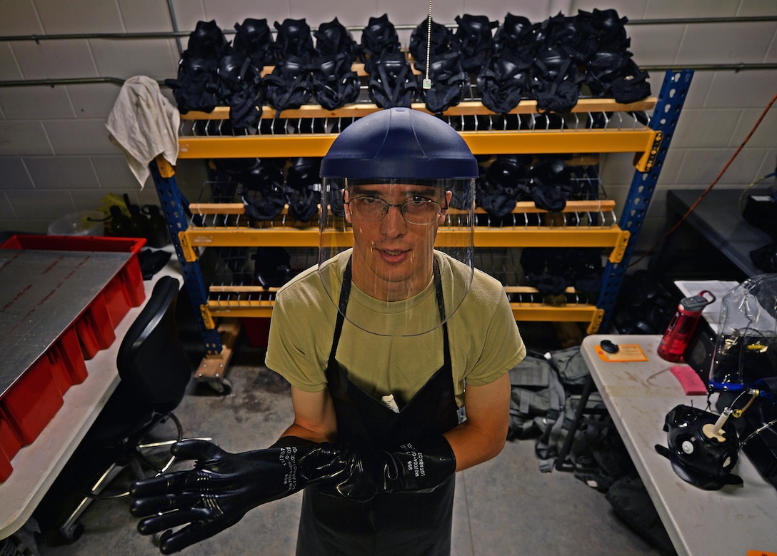 Airman 1st Class Maxwell Dean, a material management apprentice with the 1st Special Operations Logistics Readiness Squadron, puts on safety gear before sanitizing gas masks at Hurlburt Field, Fla., July 7, 2016. Materiel managers are responsible for the accounting, administering and operating equipment and supplies that are issued to Airmen around the base. (U.S. Air Force photo by Senior Airman Andrea Posey)