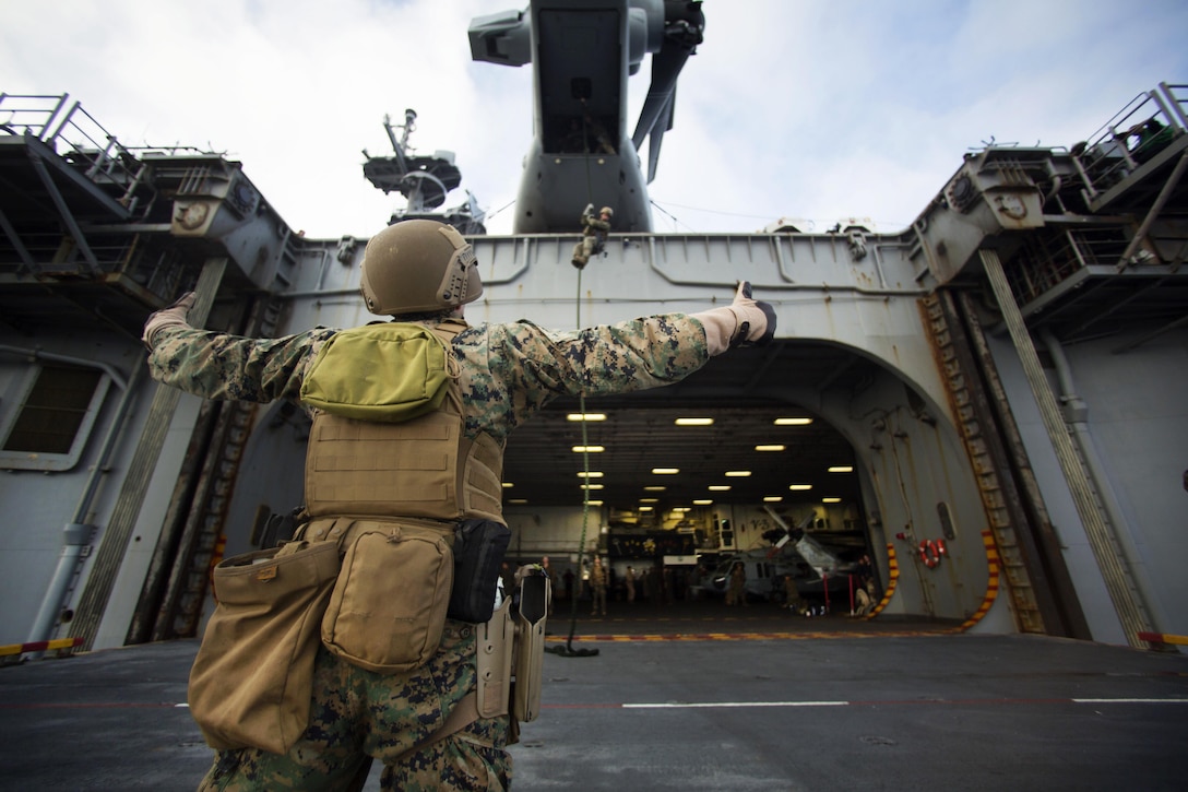 A Marine provides instructions as a member of his team conducts fast-rope training from the back of an MV-22 Osprey aircraft aboard the amphibious assault ship USS Wasp in the Atlantic Ocean, July 5, 2016. The Wasp is supporting security efforts in the U.S. 6th Fleet area of responsibility. Marine Corps photo by Lance Cpl. Koby I. Saunders