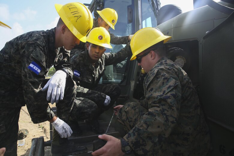 Corporal Kaleb R. Hougland, senior heavy equipment mechanic, conducts a period of instruction on the maintenance of a Caterpillar D6K Bulldozer at Puerto Castilla, Honduras, June 24, 2016. The Marines worked side-by-side on different construction and restoration projects, and shared knowledge and experience on techniques including maintenance and operation of heavy equipment. (U.S Marine Corps Photo by Cpl. Ian Ferro/Released)