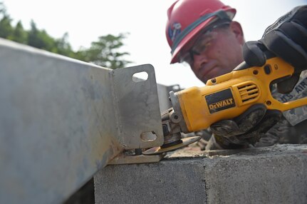 Pennsylvania National Guard Senior Master Sgt. Ronald Hinsey, 201st Rapid Engineer Deployable Heavy Operational repair Squadron Engineers structures superintendent, grinds a mounting plate to size for a new medical clinic May 3, 2016. 