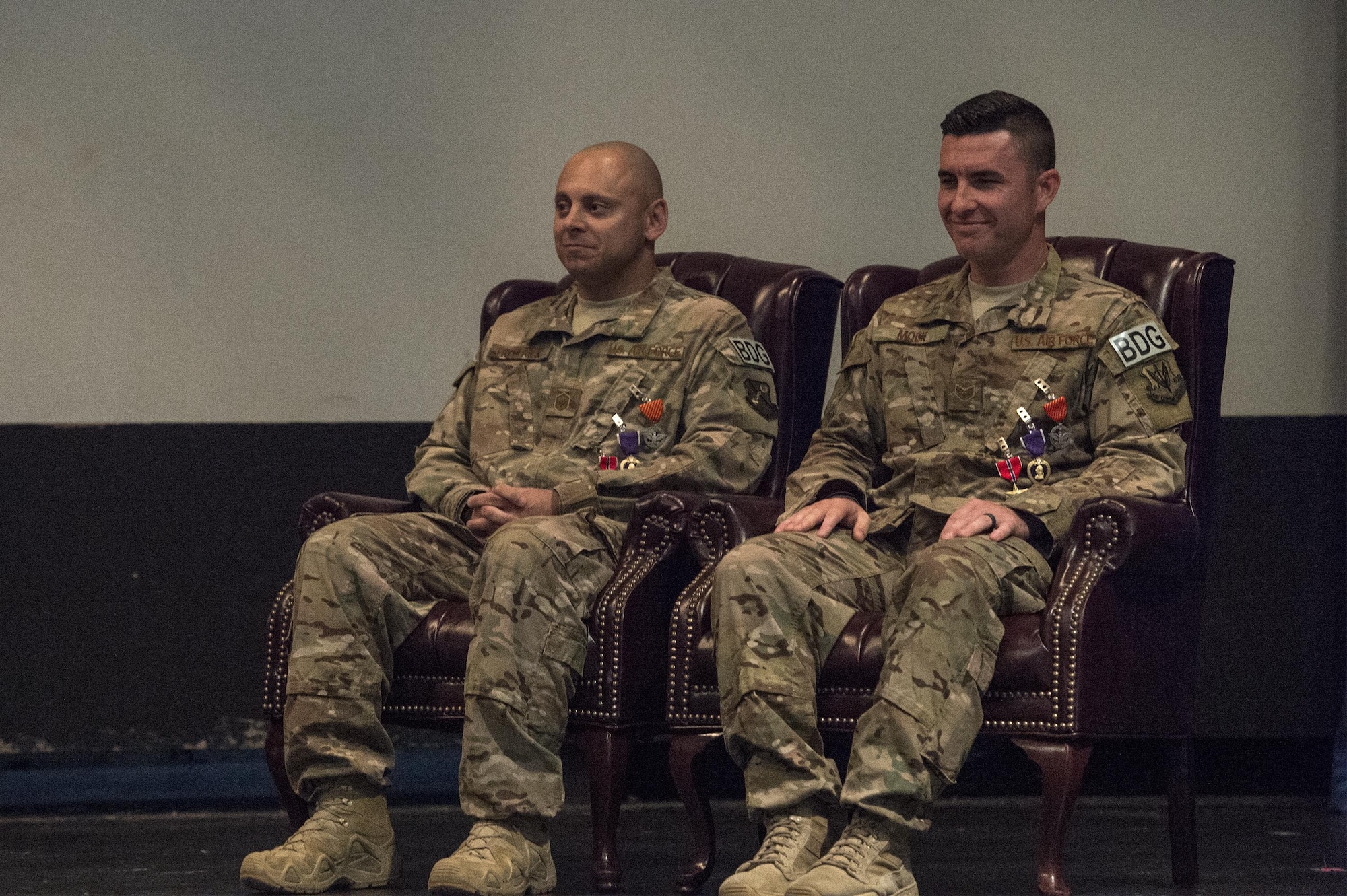 U.S. Air Force Master Sgt. Aaron Frederick, left, 93d Air Ground Operations Wing command chief executive assistant, and Staff Sgt. Bradley Mock 824 Base Defense Squadron superintendent of supply listen to remarks during a medallion ceremony, July 8, 2016, at Moody Air Force Base, Ga. Frederick and Mock disregarded their need for medical attention to ensure the well-being, safety, and evacuation of injured Airmen after an attack Dec. 21, 2015, in Southwest Asia. (U.S. Air Force photo by Airman 1st Class Janiqua P. Robinson/Released)