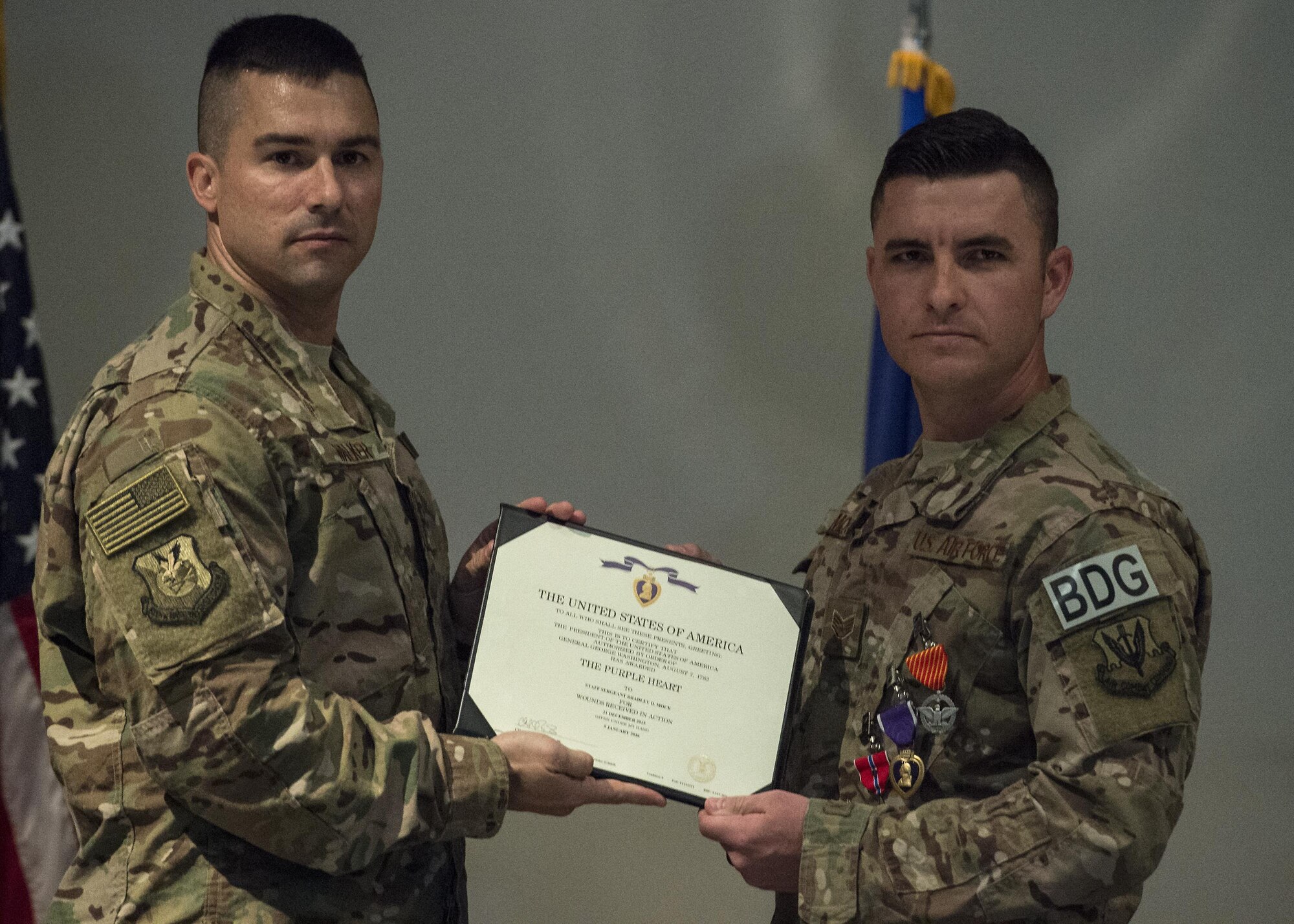 U.S. Air Force Col. Kevin Walker, left, 820th Base Defense Group commander, presents a Purple Heart certificate to Staff Sgt. Bradley Mock, 824 Base Defense Squadron superintendent of supply, during a medallion ceremony, July 8, 2016, at Moody Air Force Base, Ga. One of the medals Mock received was the Purple Heart, which is awarded for wounds or death as result of an act of any opposing armed force, international terrorist attack or as a result of military operations while serving as part of a peacekeeping force. (U.S. Air Force photo by Airman 1st Class Janiqua P. Robinson/Released)