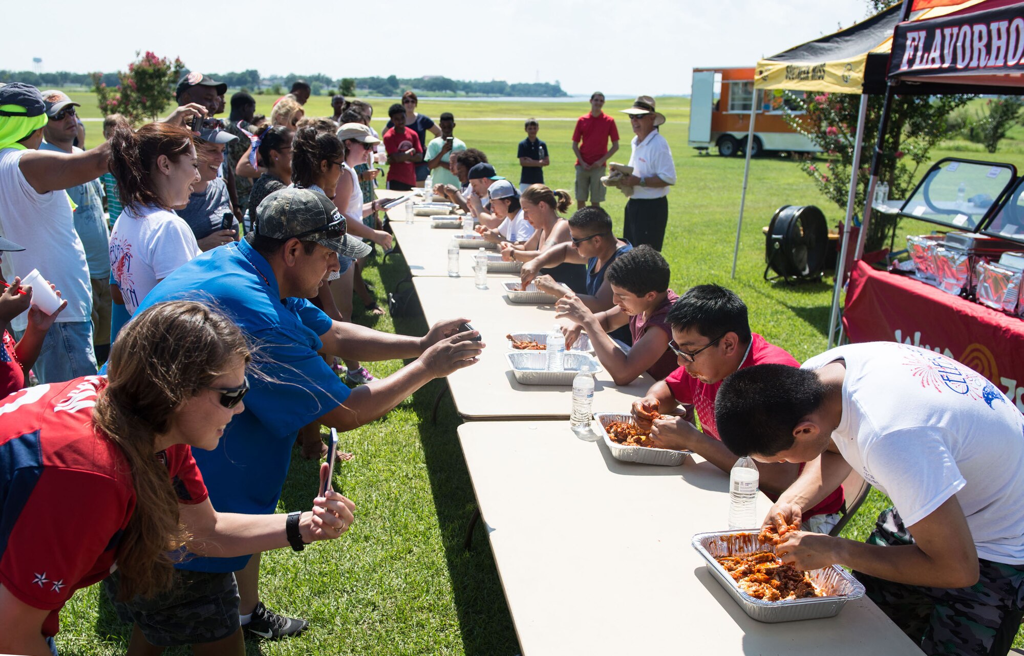 Keesler families participate in a hot wing eating competition during the Celebration of Our Nation event at Marina Park July 2, 2016, on Keesler Air Force Base, Miss. The event also included a golf scramble, mullet toss, fireworks display and music performances. (U.S. Air Force photo by Marie Floyd/Released)