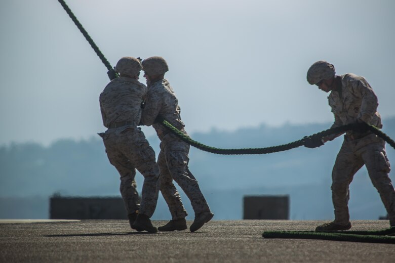 Marines with 2nd Battalion, 5th Marine Regiment, Weapons Company, Scout Sniper Platoon, prevent a rope from flailing in the rotor wash of an MV-22B Osprey with Marine Medium Tiltrotor Squadron 164 during fast-rope training aboard Marine Corps Base Camp Pendleton, Calif., June 30. The ability to fast rope enables Marines to insert into an area or structure without landing the aircraft, eliminating the need for a landing zone. (U.S. Marine Corps photo by Sgt. Lillian Stephens/Released)