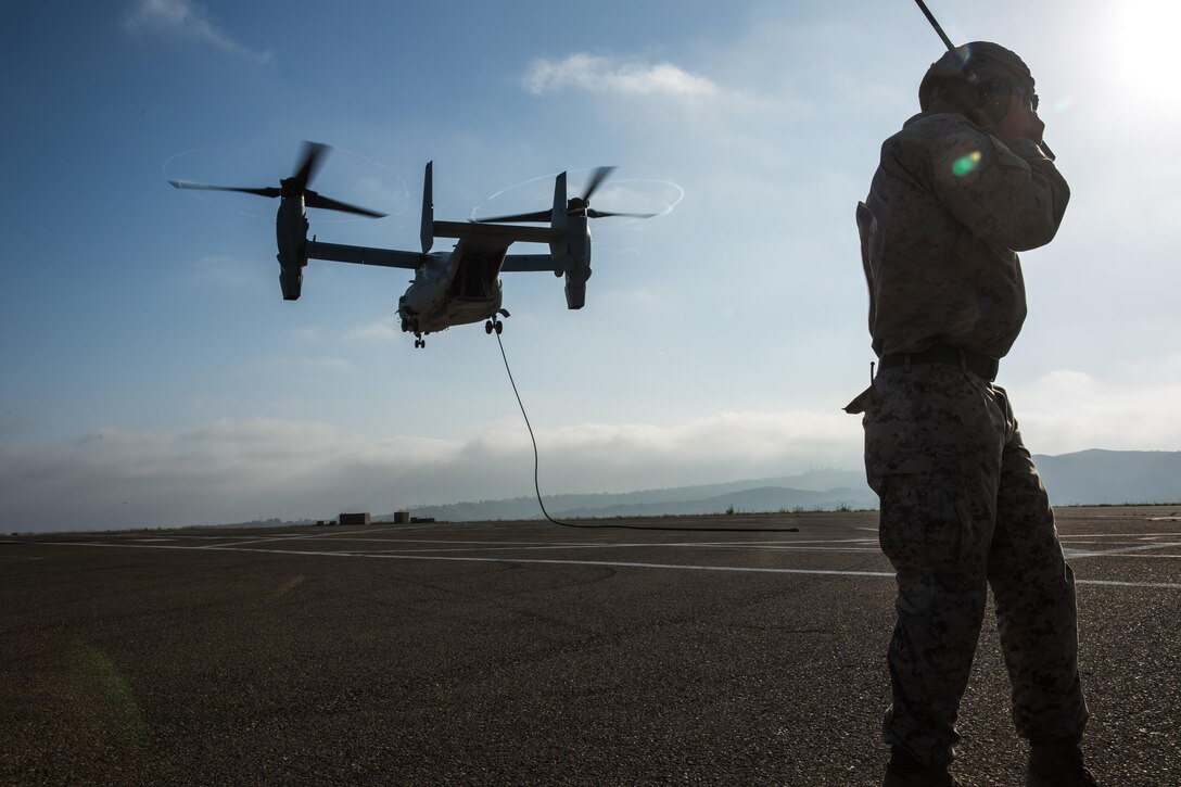 A Marine with 2nd Battalion, 5th Marine Regiment, Weapons Company, Scout Sniper Platoon, communicates with the pilots of an MV-22B Osprey with Marine Medium Tiltrotor Squadron 164 during fast-rope training aboard Marine Corps Base Camp Pendleton, Calif., June 30. The ability to fast rope enables Marines to insert into an area or structure without landing the aircraft, eliminating the need for a landing zone. (U.S. Marine Corps photo by Sgt. Lillian Stephens/Released)