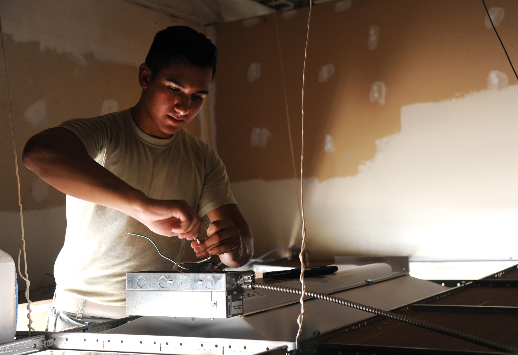 U.S. Air Force Airman 1st Class Farid Dom, a 509th Civil Engineer Squadron electrical systems apprentice, installs a light at the new Airman’s Attic at Whiteman Air Force Base, Mo., July 5, 2016. The Airman’s Attic accepts clothing and household good donations, which are offered for free to Airmen E-5 and below. (U.S. Air Force photo by Airman 1st Class Michaela R. Slanchik)