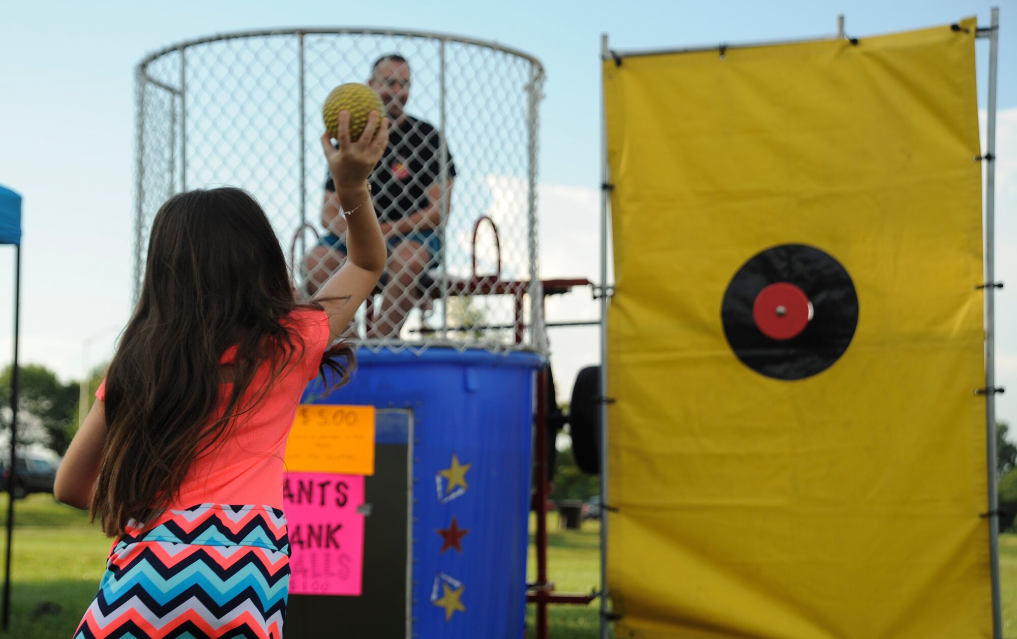 A participant of the Independence Day Celebration throws a ball toward the dunk tank button at Whiteman Air Force Base, Mo., June 30, 2016. Personnel and their families had the opportunity to send their squadrons’ first sergeants into the tank of cold water. (U.S. Air Force photo by Senior Airman Danielle Quilla)