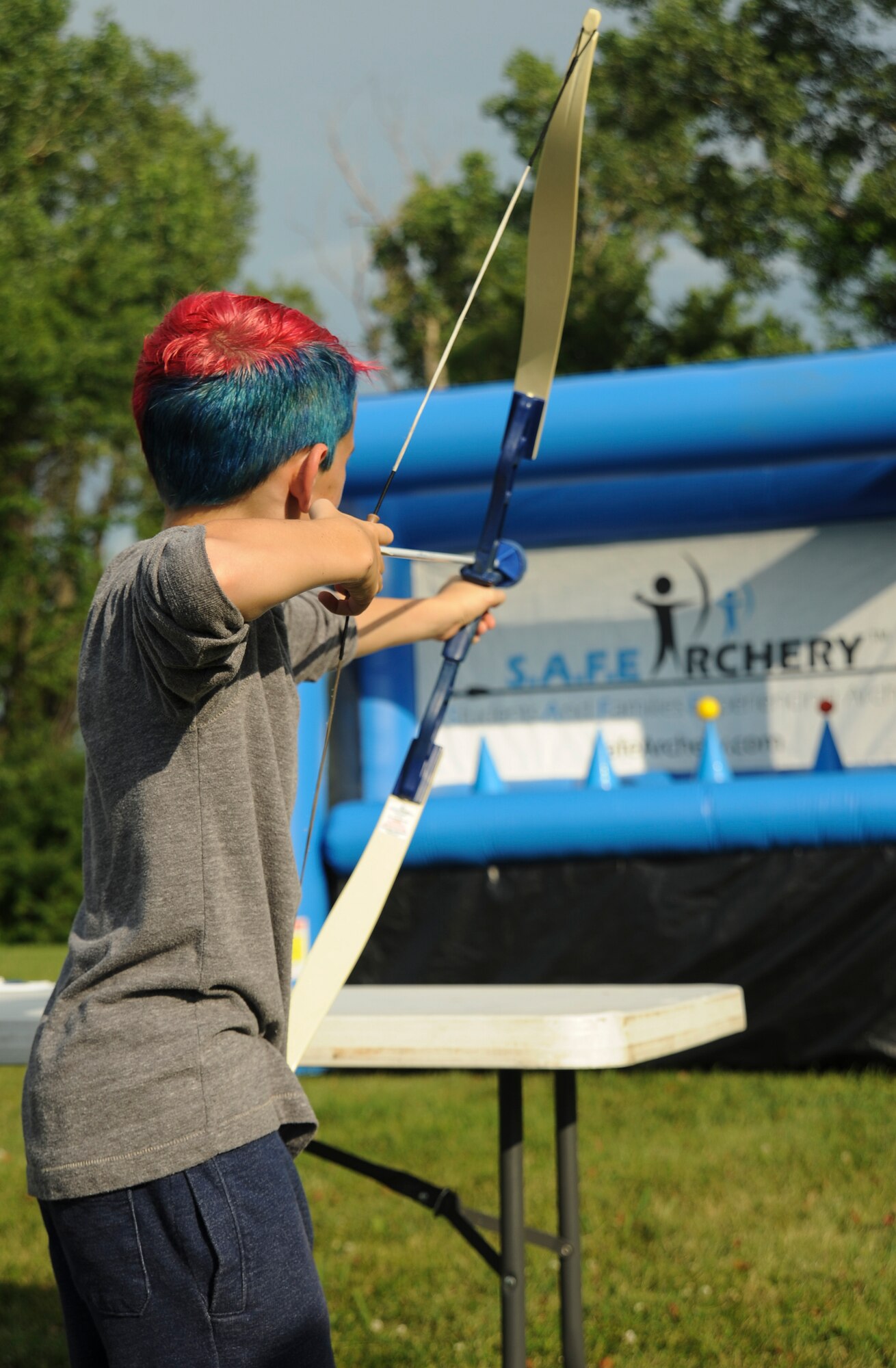 A participant of the Independence Day Celebration aims an arrow at a hover ball inflatable target at Whiteman Air Force Base, Mo., June 30, 2016. In addition to the inflatable activities, the event also included live music, a zip line, refreshments, and a face-painting and balloon station prior to an evening of fireworks. (U.S. Air Force photo by Senior Airman Danielle Quilla)
