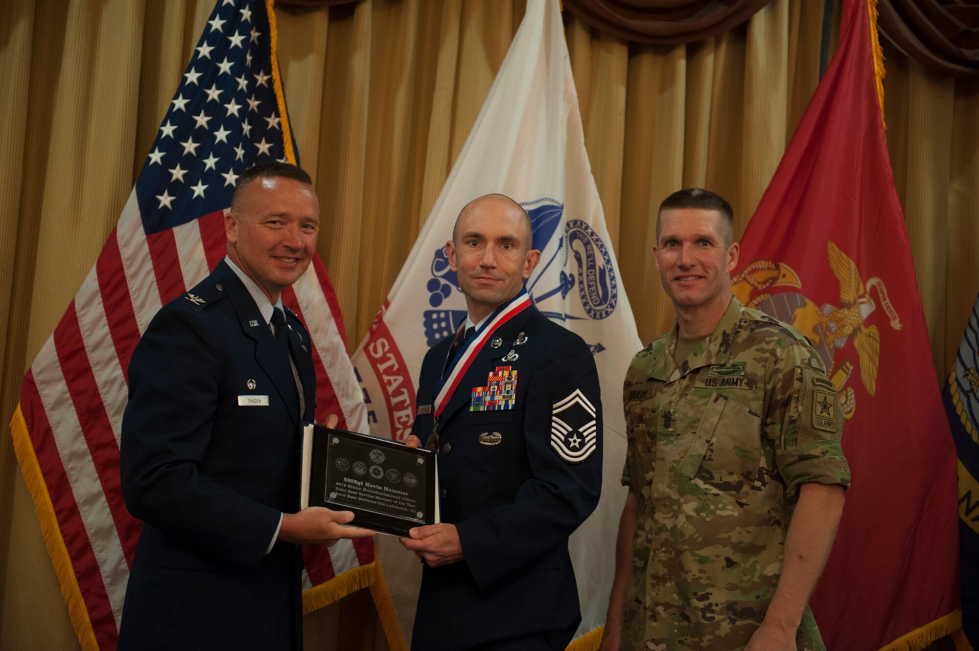 Col. Frederick D. Thaden and Sgt. Maj. of the Army Daniel Dailey present Senior Master Sgt. Kevin Hammer an award for winning the senior NCO category of the 2016 Service Member of the Year Competition at Tommy B's Community Center at Joint Base McGuire-Dix-Lakehurst, New Jersey, July 7, 2016. Hammer achieved a perfect score on the 100-question general military knowledge test during the competition, which tested competitor's physical and mental abilities. Thaden is Joint Base McGuire-Dix-Lakehurst and 87th Air Base Wing commander, and Hammer is the 87th Civil Engineer Squadron's Explosive Ordnance Disposal Flight chief. (U.S. Air Force photo by Airman 1st Class Zachary Martyn/Released) 