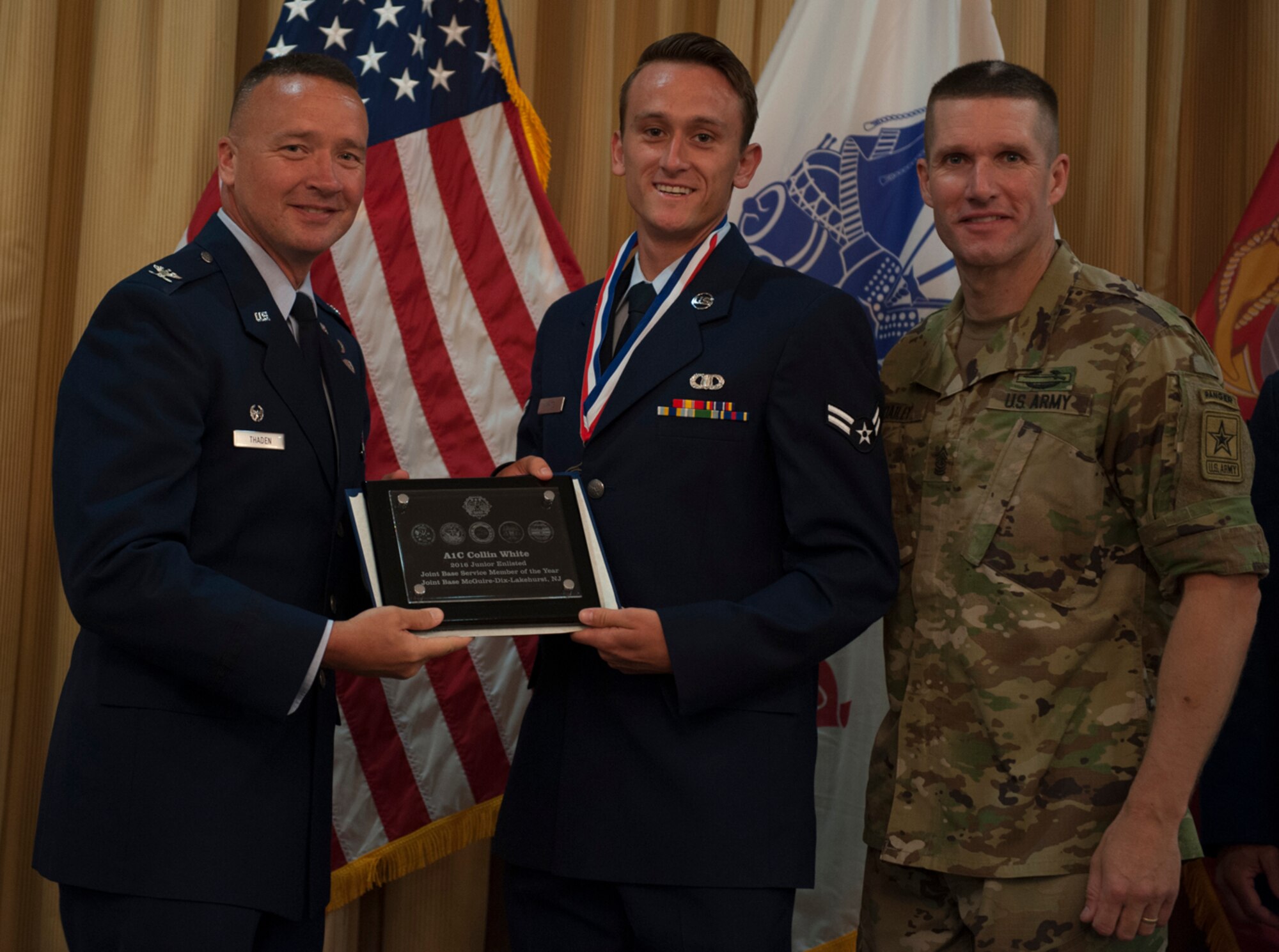 Col. Frederick D. Thaden and Sgt. Maj. of the Army Daniel Dailey present Airman 1st Class Collin White an award for victory in the junior enlisted category of the 2016 Service Member of the Year Competition at Tommy B's Community Center on Joint Base McGuire-Dix-Lakehurst, New Jersey, July 7, 2016. White scored higher than any other competitor on the virtual M4 firing range and completed his 2-mile run in less than 12 minutes. Thaden is the Joint Base McGuire-Dix-Lakehurst and 87th Air Base Wing commander, and White is an air traffic controller with the 305th Operations Support Squadron. (U.S. Air Force photo by Airman 1st Class Zachary Martyn/Released) 