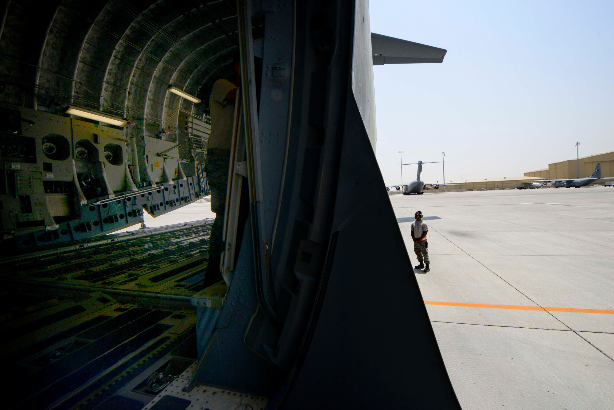 Staff Sgt. Benjamin Taylor, 8th Expeditionary Air Mobility Squadron, Aircraft Maintenance Flight instruments and flight controls craftsman, stands by as Staff Sgt. Josh Budinich, 8th EAMS, MXA aero repair craftsman, controls the C-17 Globemaster III cargo ramp during a preflight inspection June 30, 2016, at Al Udeid Air Base, Qatar. Approximately 130 Airmen from Joint Base Lewis-McChord, Wash., Joint Base Charleston, S.C., and Travis Air Force Base, Calif. work around the clock maintaining the airlift assets here. (U.S. Air Force photo/Senior Airman Janelle Patiño/Released)