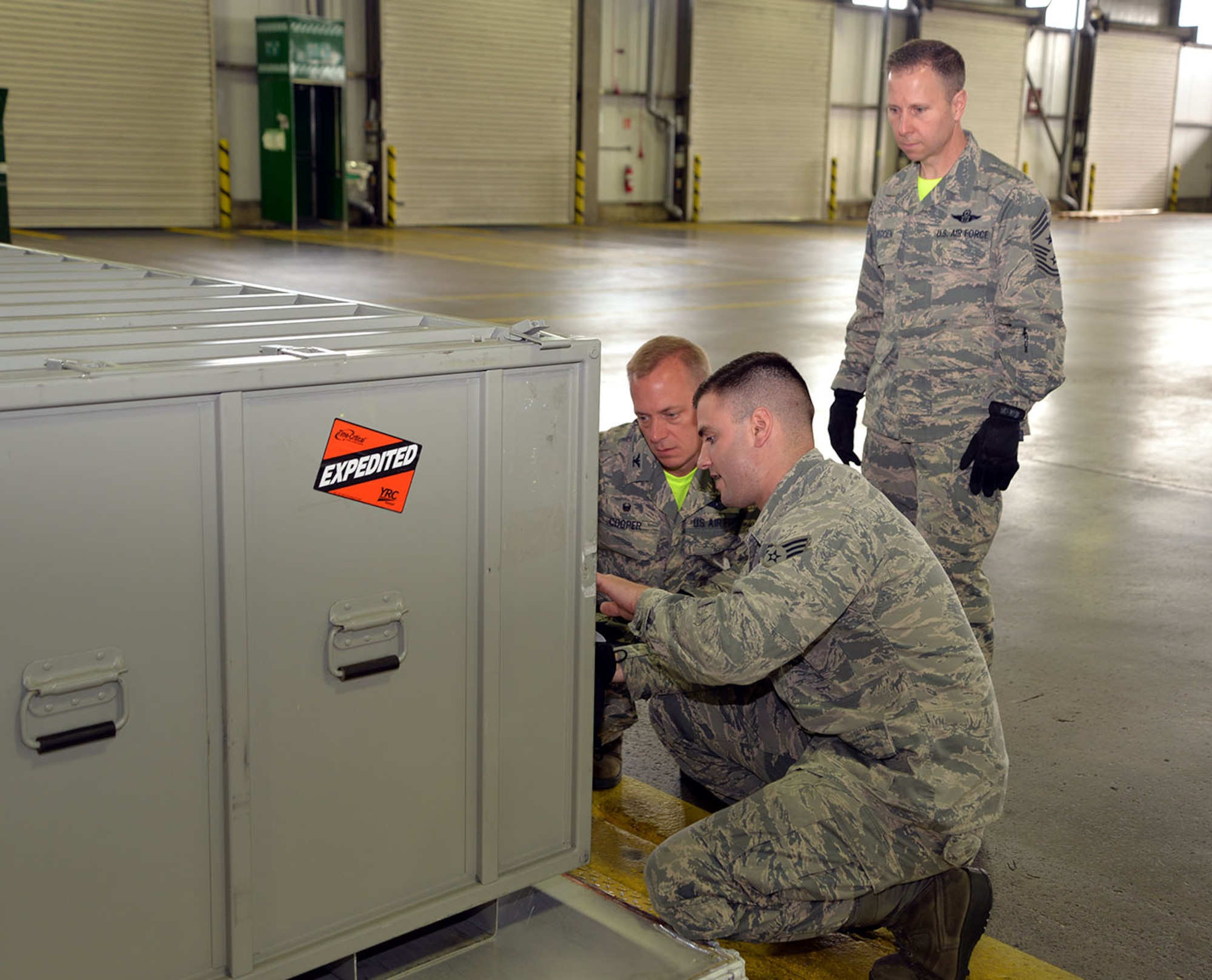 U.S. Air Force Senior Airman Logan Stahl, center, 727th Air Mobility Squadron air freight technician, explains labelling procedures to U.S. Air Force Col. Thomas Cooper, left, 521st Air Mobility Operations Wing commander, and Chief Master Sgt. Mark Redden, 521st AMOW command chief, July 1, 2016, on RAF Mildenhall, England. Cooper recently took command of the 521st AMOW and visited the 727th AMS to meet Airmen and Ministry of Defence civilians under his command. (U.S. Air Force photo by Karen Abeyasekere/Released)