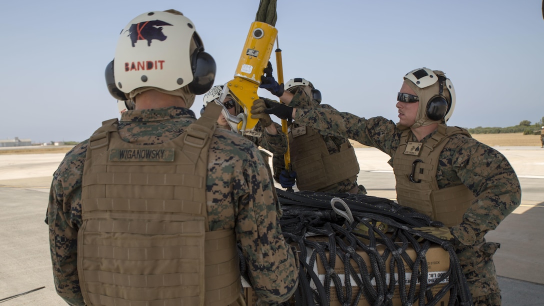 Landing support specialists with Combat Logistics Battalion 2, Special Purpose Marine Air-Ground Task Force-Crisis Response-Africa, attach a 1,098 pound pallet of Meals, Ready to Eat to an MV-22B Osprey during a helicopter support team exercise at Naval Station Rota, Spain, July 6, 2016. This training prepares the Marines to efficiently attach cargo to the aircraft and helps qualify air crew in the mission-essential task of rapid insertion and extraction.