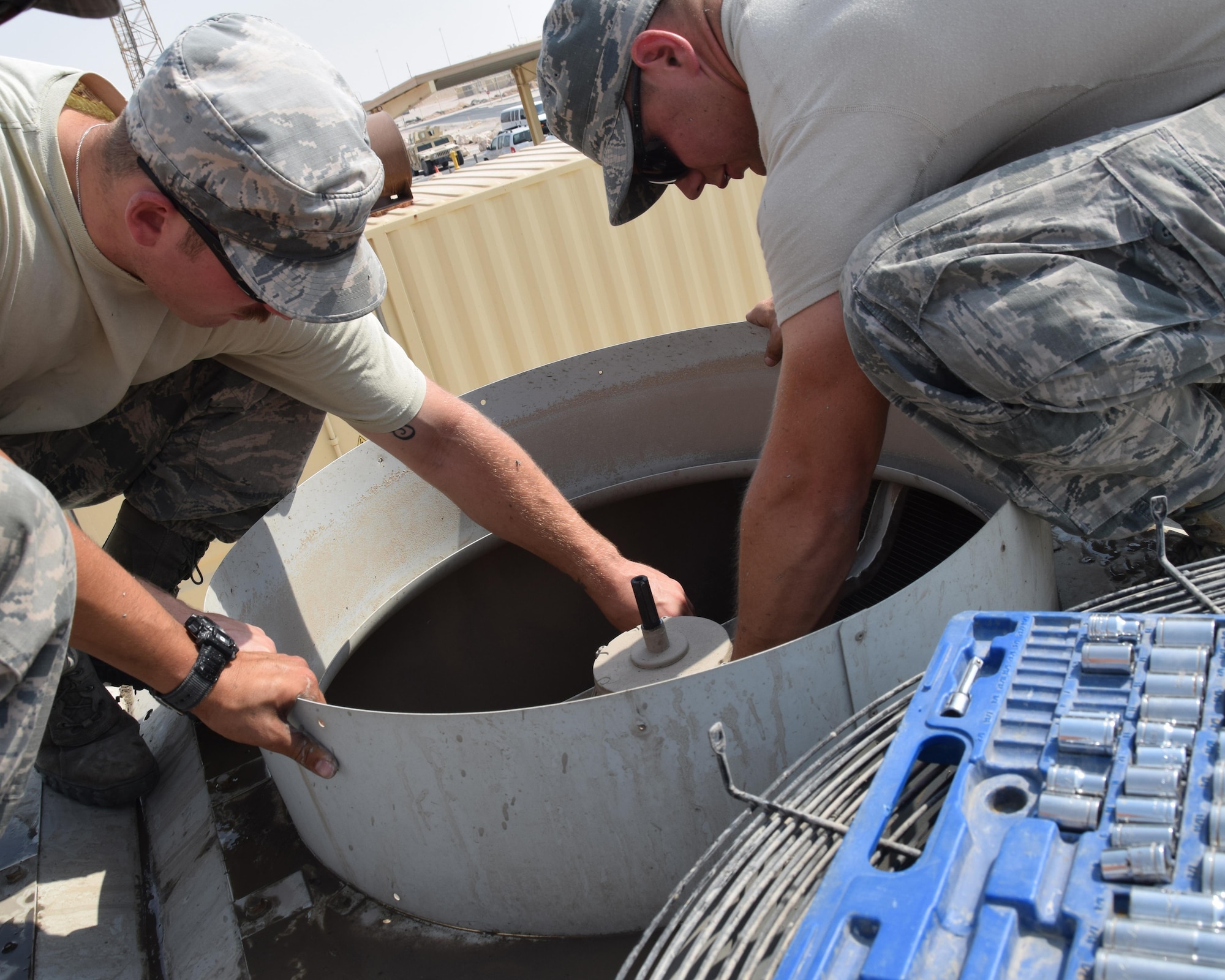 Staff Sgt. Erik Nelson right) and Senior Airman Shaun Berger, 379th Expeditionary Civil Engineering Squadron heating ventilation air conditioning and refrigeration journeyman remove a motor from a fan on a chiller behind building 6671 June 27, 2016, at Al Udeid Air Base, Qatar. Berger removed the motor, which had bad windings and needed replacement. Hvac/r specialists are responsible for maintaining the systems that keep places like the wing operations center, cool.  (U.S. Air Force photo/Technical Sgt. Carlos J. Trevino/Released)