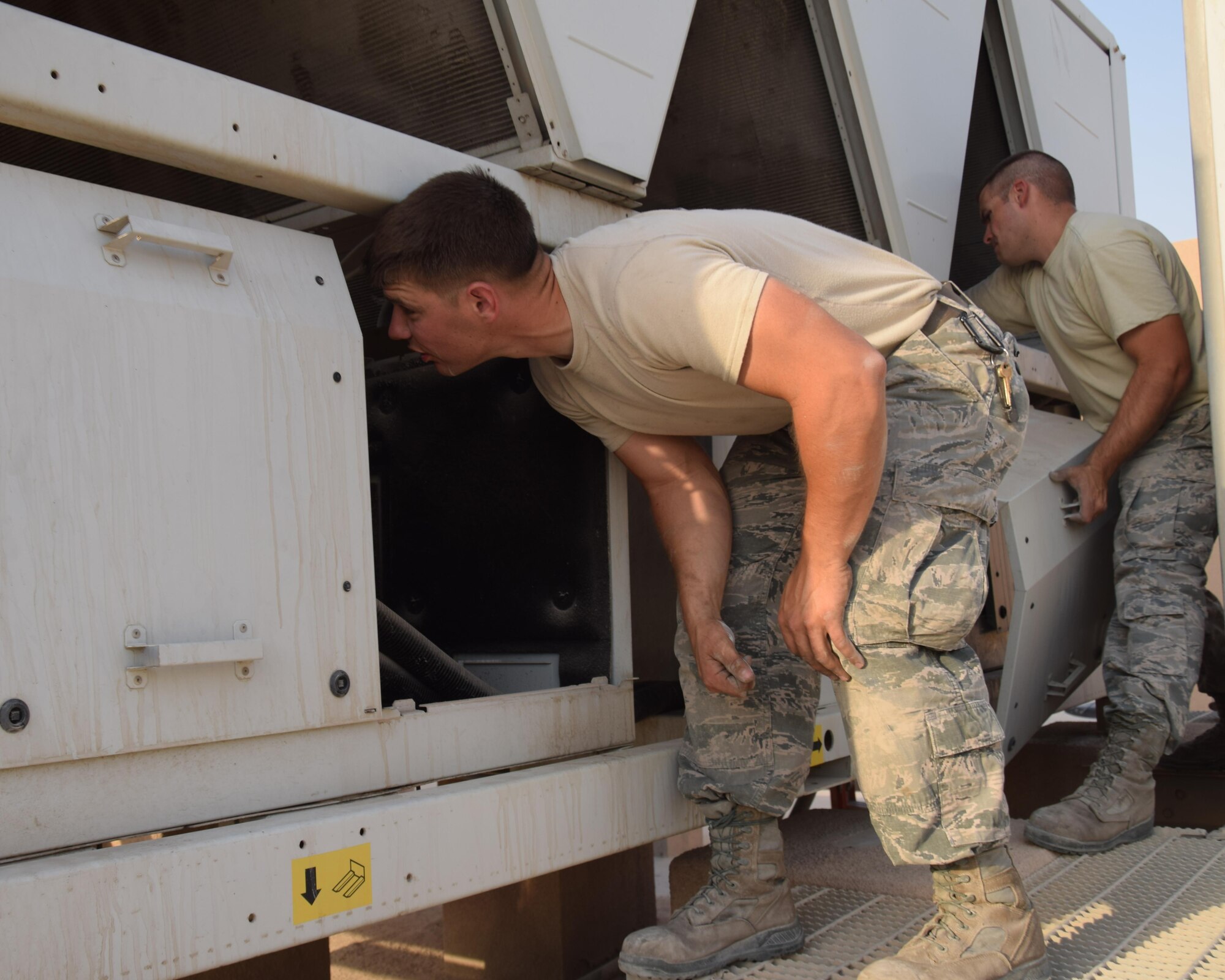 Senior Airman Jesse Fentross and Staff Sgt. Erik Nelson, 379th Expeditionary Civil Engineering Squadron heating ventilation air conditioning and refrigeration journeyman remove panels on a chiller in search of a electrical short  behind building 6671 June 27, 2016, at Al Udeid Air Base, Qatar. Hvac Airmen ensure safe and healthy living and working condtions for more than 10,000 U.S. and coalition forces stationed here. (U.S. Air Force photo/Technical Sgt. Carlos J. Trevino/Released)