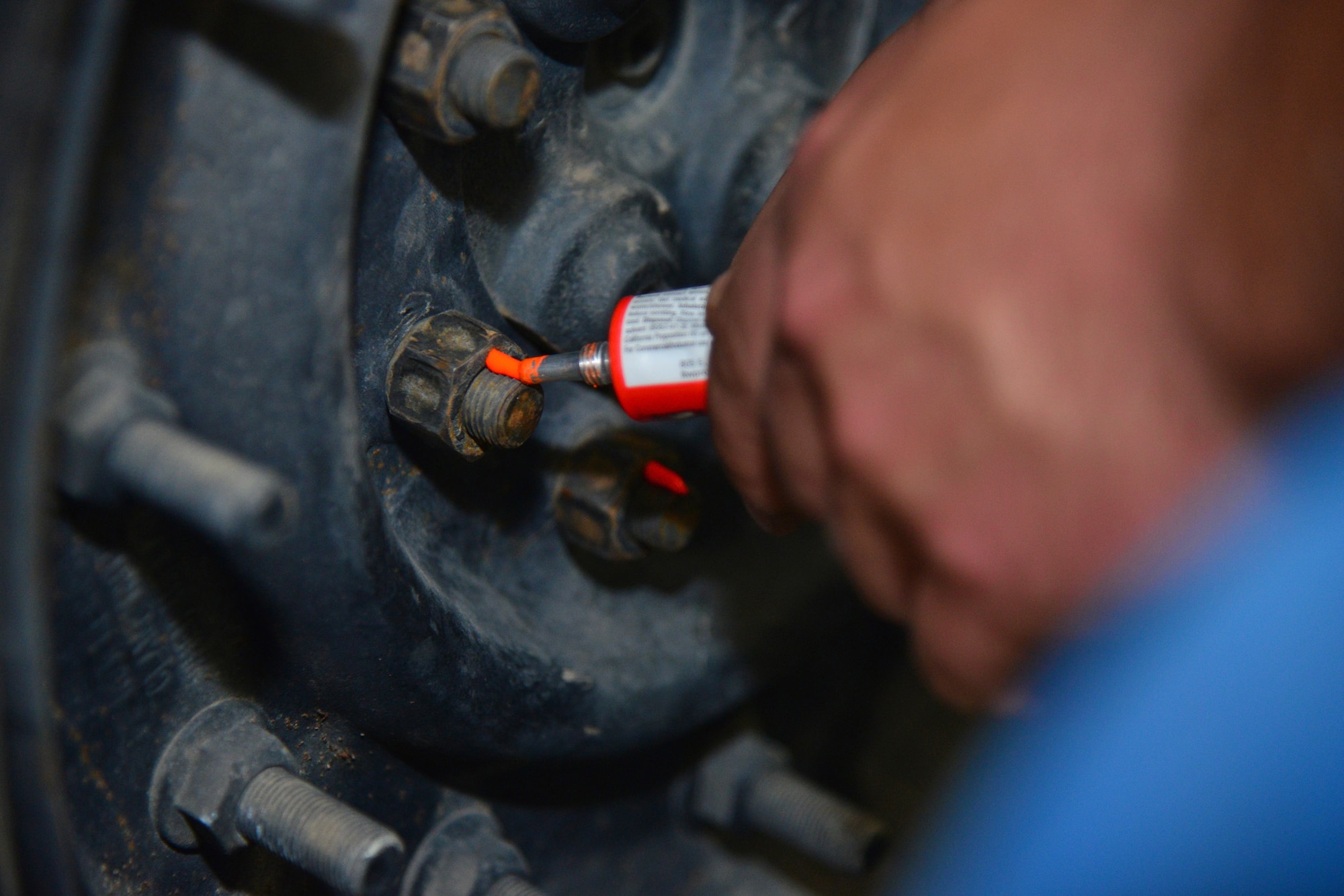 Senior Airman Hunter Dombek, 341st Logistics Readiness Squadron mission generating vehicular equipment maintenance technician, places orange paint onto the bolts of a tire July 7, 2016, at Malmstrom Air Force Base, Mont. The paint shows the Airmen completion of the job at the required settings and prevents manipulation to the bolts after the tire shop is finished. (U.S. Air Force photo/Airman 1st Class Daniel Brosam)