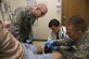 Scott Flewellyn, center right, a medical student, inserts a vaccination into a patient’s knee. Capt. (Dr.) Dylan Tracy, left, a Family Medicine residency student, observes the injection, while Capt. (Dr.) Trevor Smith, a faculty member, guides the process and mentors the students. The residency program is one in which residents work with patients and are able to be guided and mentored by experienced faculty members. (U.S. Air Force photo/Airman 1st Class Gwendalyn Smith)