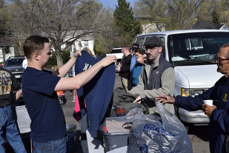 PETERSON AIR FORCE BASE, Colo. – Airman 1st Class Erik Cochran, left, and Airman 1st Class Andrew Klegraefe, center, help a visitor find clothing at a More Than a Meal event. Members of Team Pete get involved in the community by volunteering with the organization and others through the Junior Enlisted Association. (Courtesy photo) 
