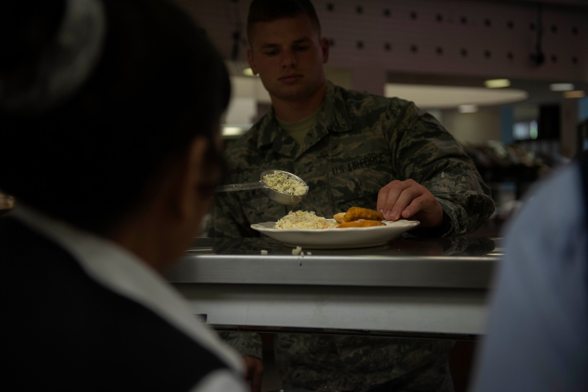 A Team Scott servicemember grabs his plate after receiving rice at the Nightingale Inn Dining Facility at Scott Air Force Base, Illinois, June 29, 2016. The dining facility has breakfast from 6 to 8 a.m. Monday through Friday, lunch from 11 a.m. to 1p.m. Monday through Friday, an evening meal 4 p.m. to 6 p.m. daily, a "grab-n-go" from 6 p.m. to 8 p.m. daily, and brunch 6 a.m. to 1 p.m. Saturday, Sunday and on holidays. (U.S. Air Force photo/Senior Airman Jake Eckhardt)