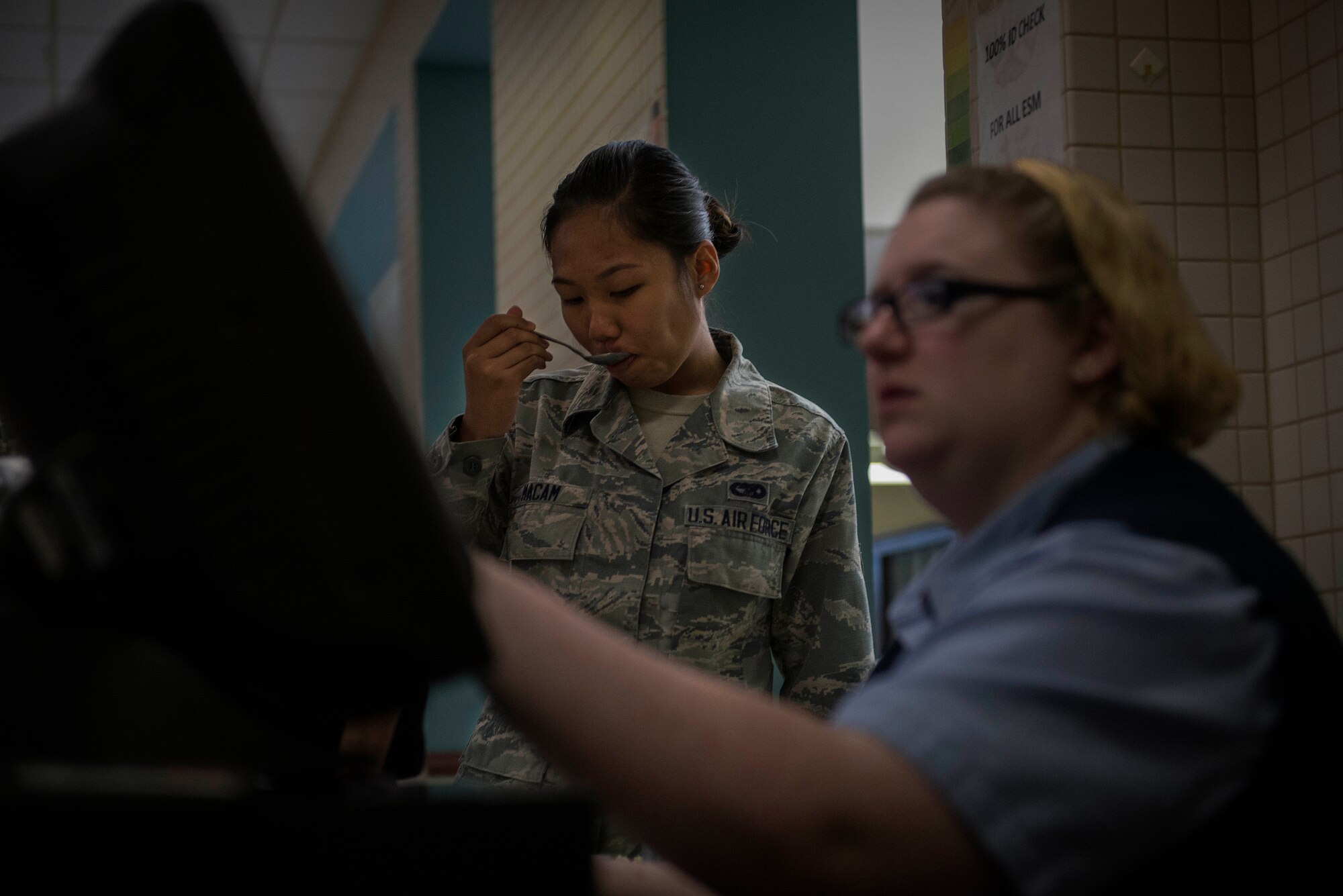 A Team Scott servicemember takes a bite of her food as she pays for it at the Nightingale Inn Dining Facility at Scott Air Force Base, Illinois, June 29, 2016. On average, the dining facility serves 400-500 people a day. (U.S. Air Force photo/Senior Airman Jake Eckhardt) 