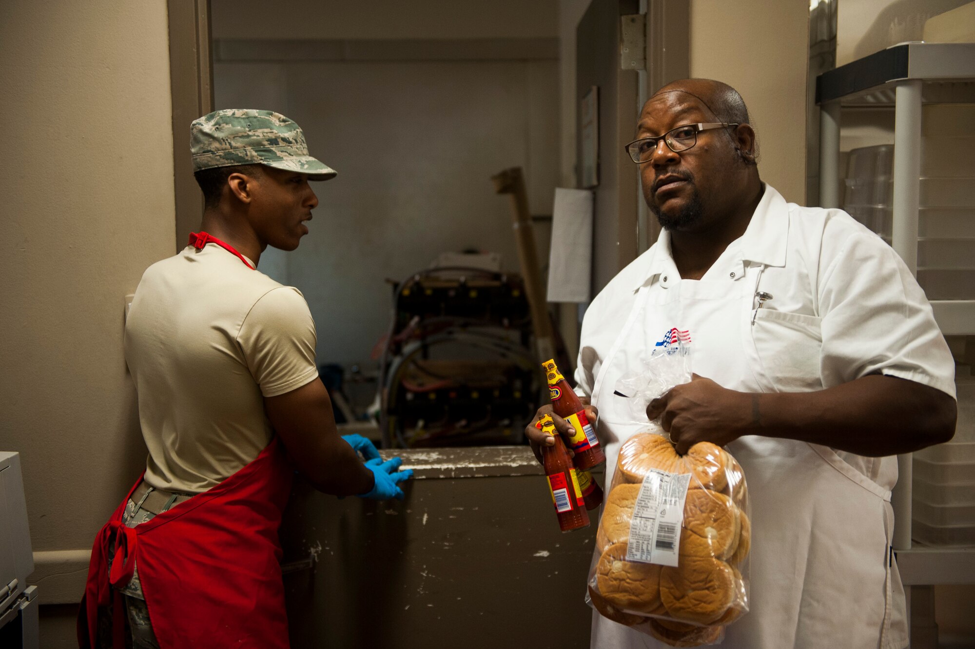 Senior Airman Kenneth LaGarde, 375th Force Support Squadron food service specialist, and Nathan Rice, 375th FSS chefs, grab supplies to prepare lunch at the Nightingale Inn June 29, 2016, at Scott Air Force Base, Illinois. The Nightingale Inn provides meals for all Airmen living in the dorms, as well as servicemembers temporarily assigned to the base. (U.S. Air Force photo by Staff Sgt. Clayton Lenhardt/Released)