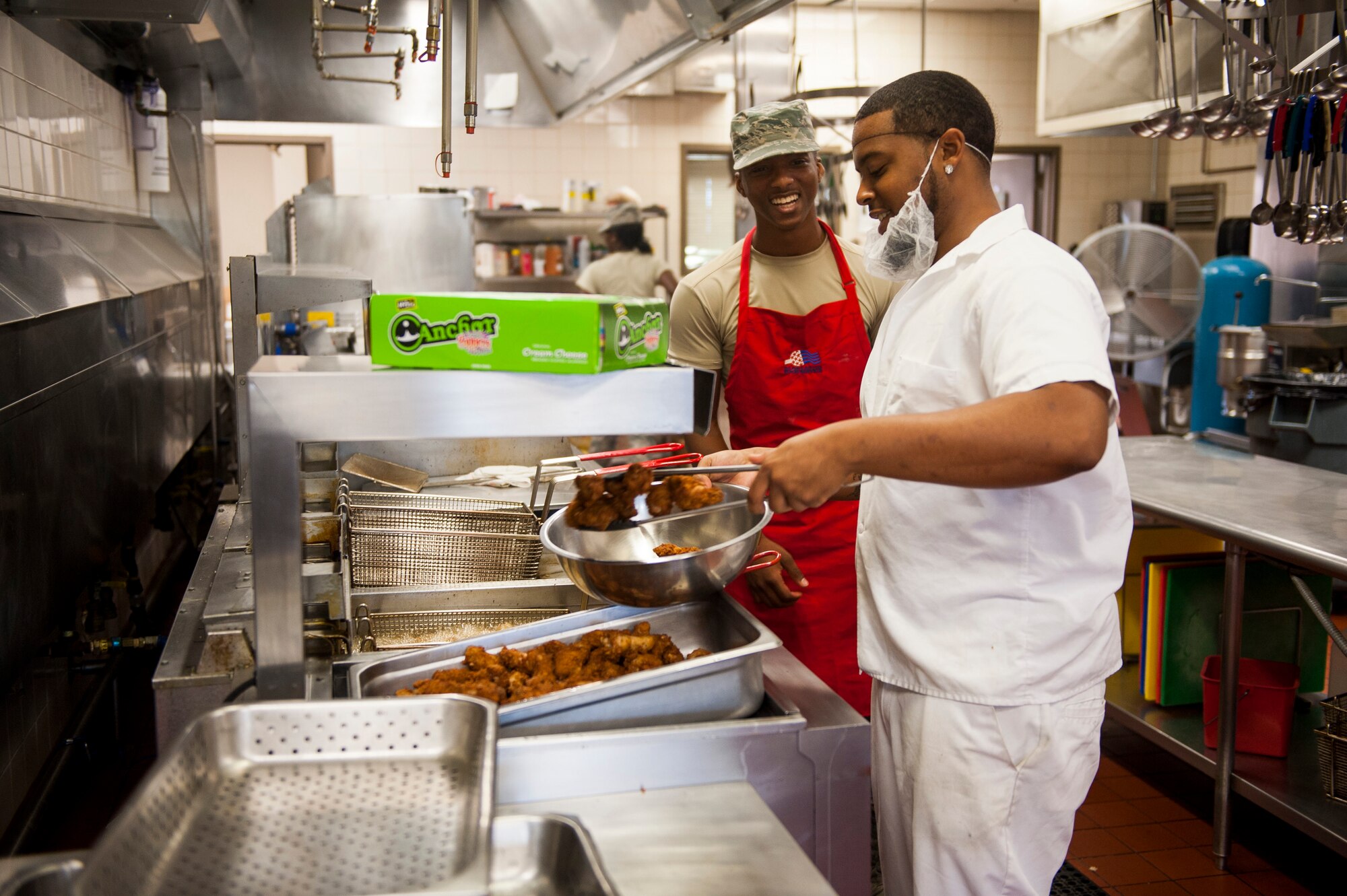 Senior Airman Kenneth LaGarde, 375th Force Support Squadron food service specialist, and Joel Young, 375th FSS chef, grab supplies to prepare wings at the Nightingale Inn June 29, 2016, at Scott Air Force Base, Illinois. The Nightingale Inn employs a team of active duty, reserve, national guard and civilians to prepare each meal. (U.S. Air Force photo by Staff Sgt. Clayton Lenhardt/Released)