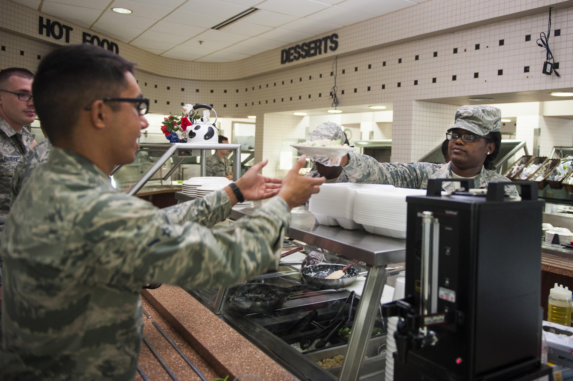 Airman 1st Class Zachari Doss, 126th Force Support Squadron food services apprentice, hands a dish to a patron at the Nightingale Inn June 29, 2016, at Scott Air Force Base, Illinois. The Nightingale Inn provides meals for all Airmen living in the dorms, as well as servicemembers temporarily assigned to the base.(U.S. Air Force photo by Staff Sgt. Clayton Lenhardt/Released)