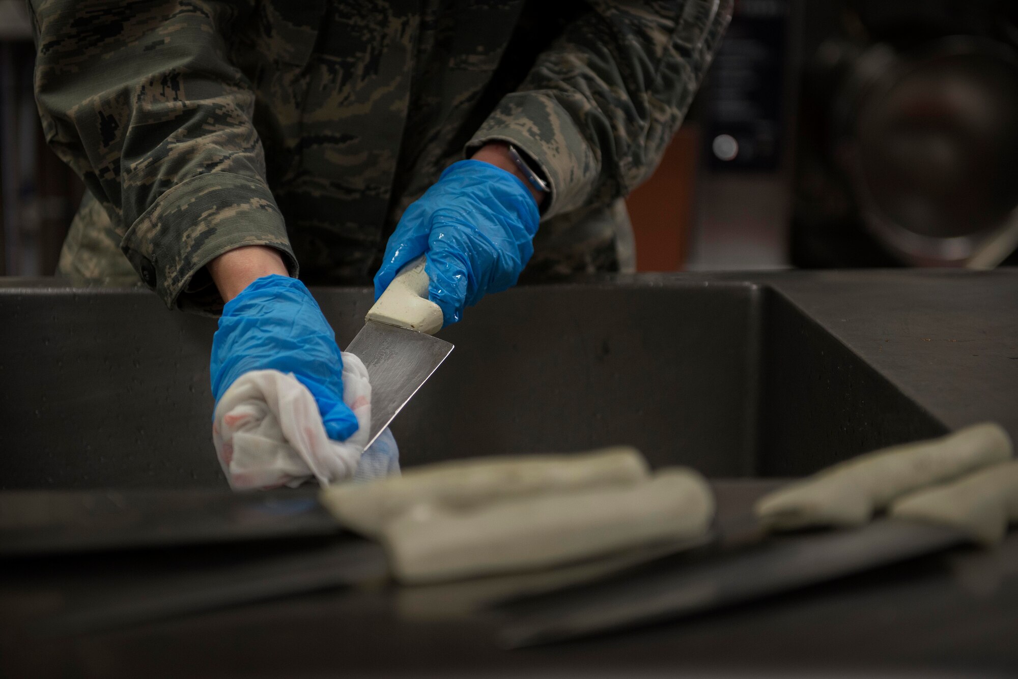 Airman 1st Class Kelly Drury, 126th Air National Guard services apprentice, cleans the knives that were used to prepare food at the Nightingale Inn Dining Facility at Scott Air Force Base, Illinois, June 29, 2016. On anverage, it takes the Scott dining facility staff an hour and a half to prepare food for one of the periods they serve food. (U.S. Air Force photo/Senior Airman Jake Eckhardt)