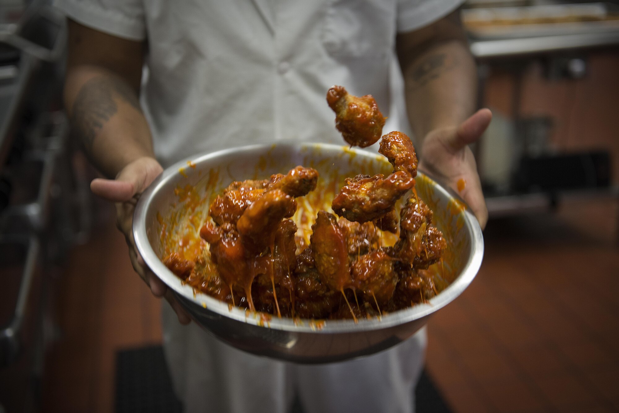 Joel Young, Nightingale Inn Dining Facility chef, mixes chicken wings with a sauce at Scott Air Force Base, Illinois, June 29, 2016. The dining facility provides a variety of foods for each meal. (U.S. Air Force photo/Senior Airman Jake Eckhardt)