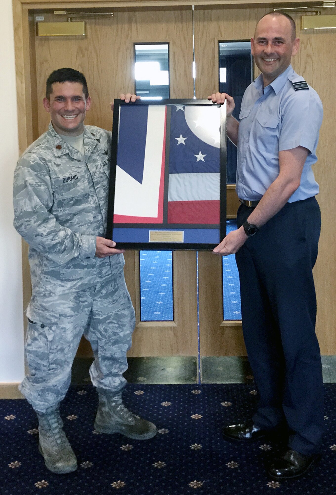 RAF FYLINGDALES, UK - Maj. Ryan Durand, 21st Operations Group liaison officer, presents a U.S. and United Kingdom flag that was flown over Peterson Air Force Base to Squadron Leader Tim Adcock, Officer Commanding Operations Squadron and president of Mess Committee, for display in the RAF Fylingdales' Officer's Mess. These two flags demonstrate the 50+ years of combined operations between the two countries. Durand presented the flags to show his appreciation for the support he received the past two years. (courtesy photo)