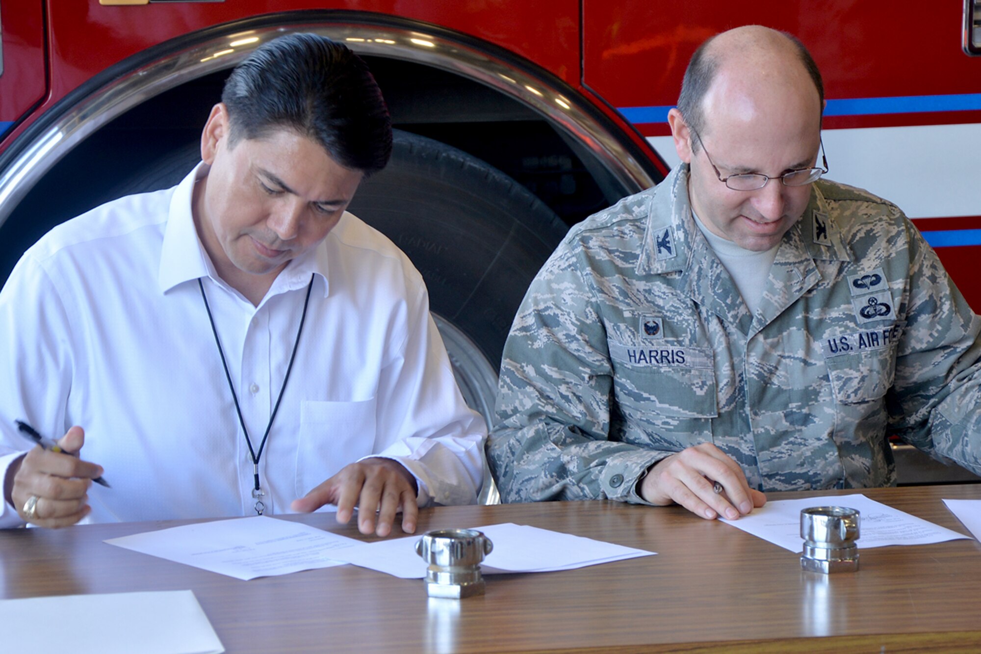 Daniel Valenzuela, San Angelo city manager, and Col. Christopher Harris, 17th Mission Support Group Commander, sign a memorandum of understanding at the Fire Truck maintence building on Goodfellow Air Force Base, Texas, July 8, 2016. This is the 13th such agreement between Goodfellow and the City of San Angelo. (U.S. Air Force photo by Airman 1st Class Randall Moose/Released)